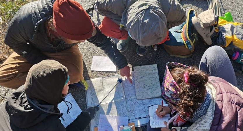 a group of people examine a map that is spread out on the ground